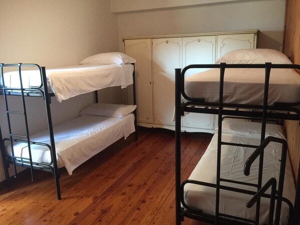 A room with bunk beds, wooden flooring, and a white wardrobe. - Agriturismo Cargandino (Mezzomerico)