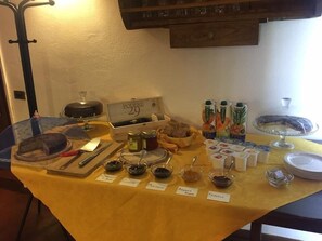 A buffet table with various food items and condiments, including jars labeled "Frasole," "Marrone," and "Coccoe," along with juice cartons and a cake on a glass stand.