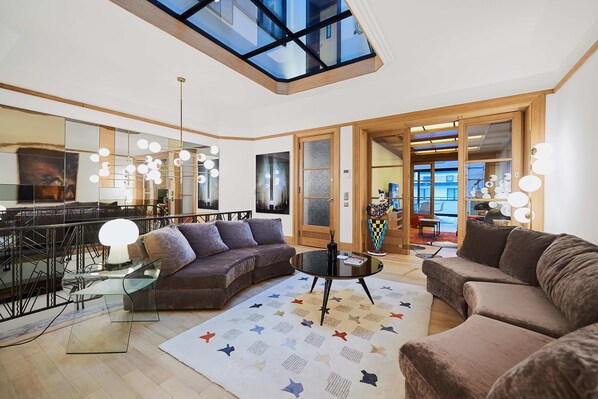 Relax in this stylish living room with a high ceiling, skylight, and comfortable sectional sofa.