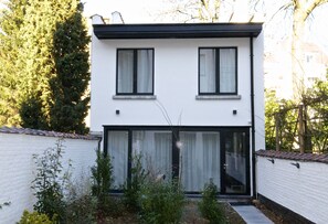 Stylish two-story residence with a clean design, featuring a white facade, black window frames, and a flat roof.