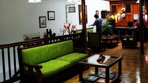 A lobby with a wooden ceiling, a green sofa, a coffee table, and a bar area. - Hospedaje Casa Real (Salamina)