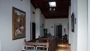 A hallway with a wooden ceiling, a painting on the wall, and a staircase leading to another room. - Hospedaje Casa Real (Salamina)