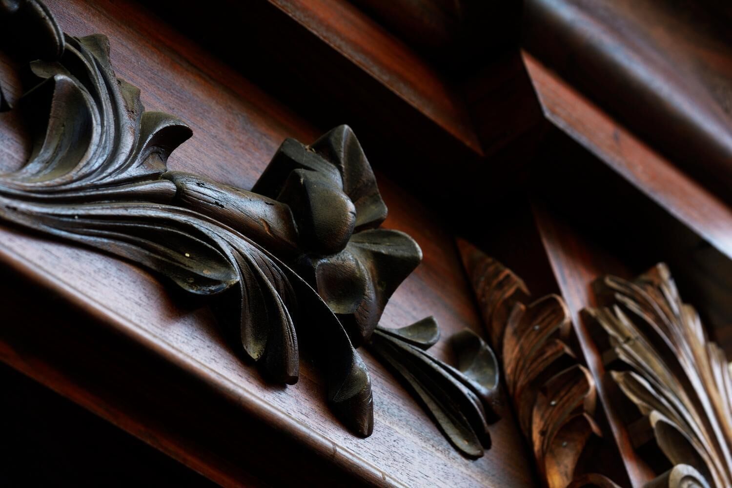 A close-up of ornate wooden carvings on a piece of furniture.