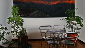 A dining area with a table and chairs, a potted plant, and a large landscape painting on the wall. - Hospedaje Casa Real (Salamina)