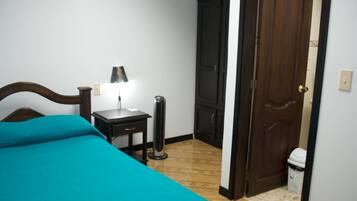 Un dormitorio con cama, mesita de noche, lámpara, calefactor, armario y puerta.
