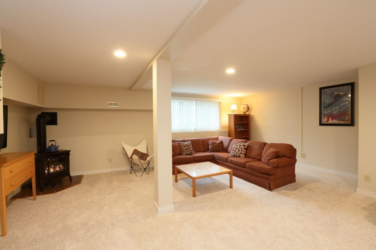 A living room with a brown sofa, a wooden coffee table, a chair, a fireplace, and a bookshelf.