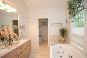 Un baño moderno con un espejo grande, una bañera y un lavabo.