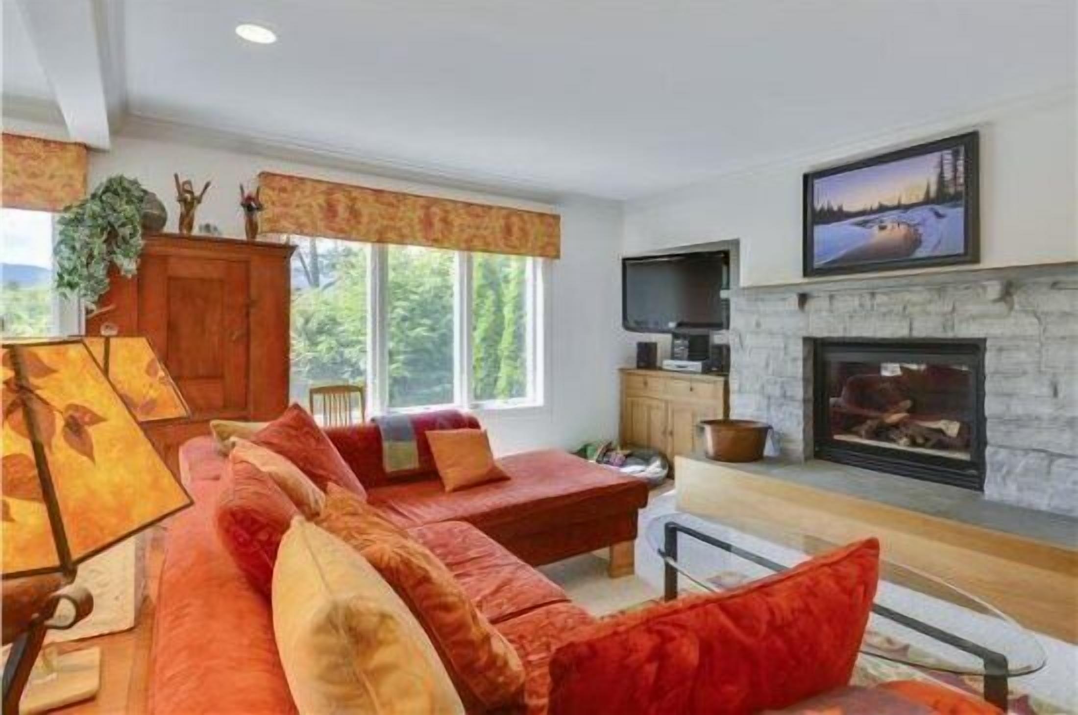 A cozy living room with a red sofa, a fireplace, and a television.