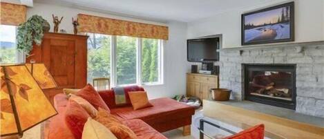 A cozy living room with a red sofa, a fireplace, and a television.
