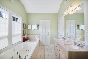 A bathroom with a large bathtub, two sinks, and a vanity with a mirror. - 700 B Topnotch (Stowe)