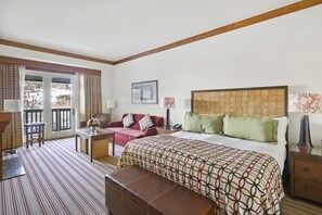 A hotel room with a bed, a sofa, a desk, and a balcony with curtains. - 1228/1230 Double Studio @ The Lodge at Spruce Peak (Stowe)