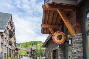 A wooden building with a sign reading "The Beanery Stowe, Vermont" and stone accents. - 1228/1230 Double Studio @ The Lodge at Spruce Peak (Stowe)