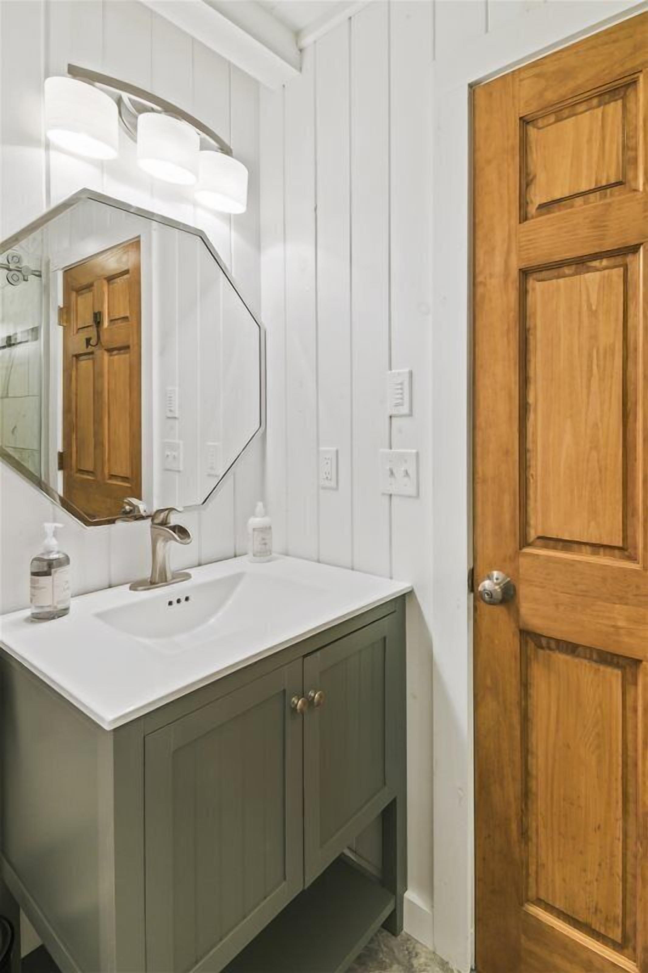 A bathroom with a white sink, a mirror, and a wooden door.