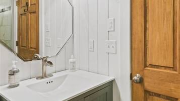 A bathroom with a white sink, a mirror, and a wooden door.