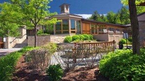 Una casa moderna con una escalera de piedra, amplios ventanales y un jardín cuidado.