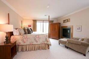 A bedroom with a bed, a nightstand, a dresser, a sofa, and a fireplace. - 4 BR Dog-friendly Overlook at Topnotch (Stowe)