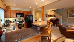 Una cocina moderna con encimeras de granito, electrodomésticos de acero inoxidable y armarios de madera.