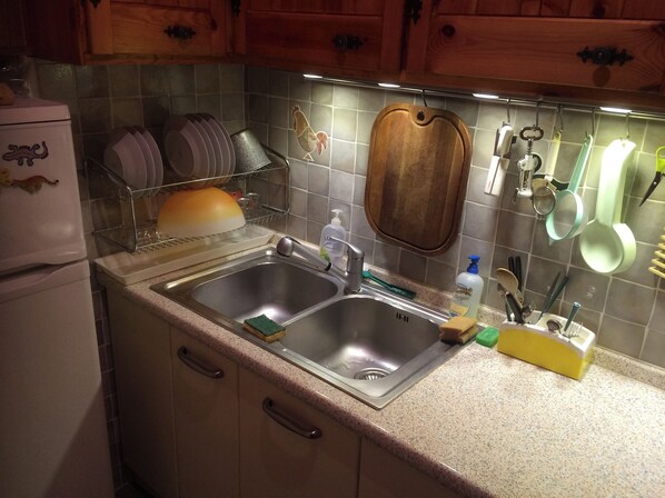 A kitchen with a stainless steel sink, wooden cabinets, and a dish rack. - Group Apartment (Gressoney-Saint-Jean)