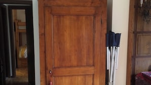 Un meuble en bois, avec une pancarte au-dessus, des béquilles appuyées contre, et une porte-fenêtre donnant sur une autre pièce.