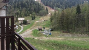 Un paysage montagneux avec une route menant à un petit bâtiment, entouré d’une forêt dense.