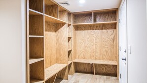 A walk-in closet with multiple wooden shelves and a bench. - Americana at Topnotch Overlook (Stowe)