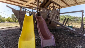 A playground with two slides and a wooden play structure. - Elite Cabins and RV Park (Big Spring)