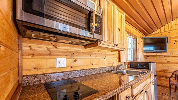 A kitchen with granite countertops, stainless steel appliances, wooden cabinets, and a built-in oven. - Elite Cabins and RV Park (Big Spring)