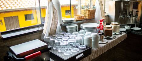 Una encimera de cocina con platos apilados, vasos y una máquina de café.