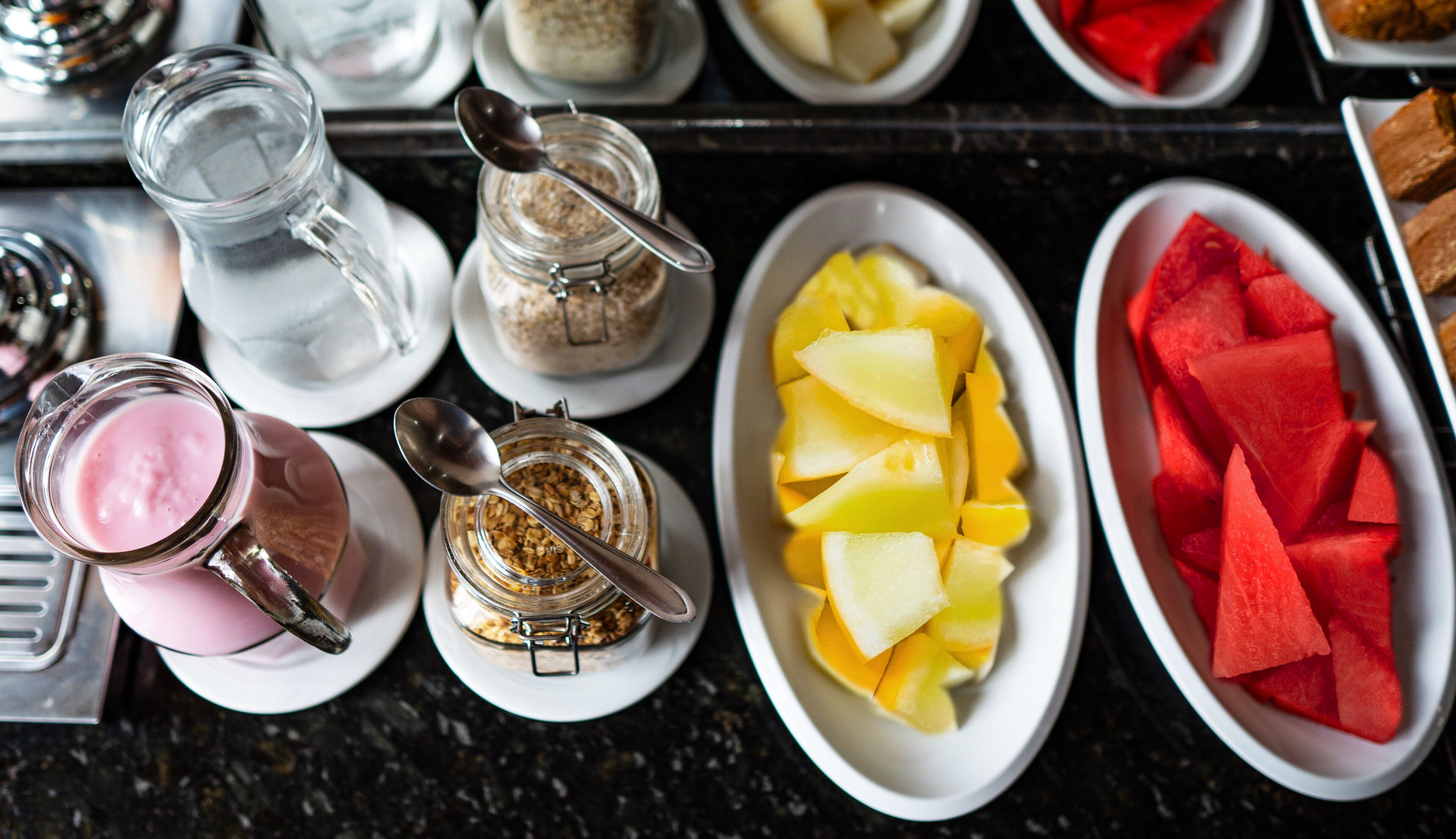 En morgenmadsbuffet med et udvalg af madvarer, herunder frugt, yoghurt og müslis.