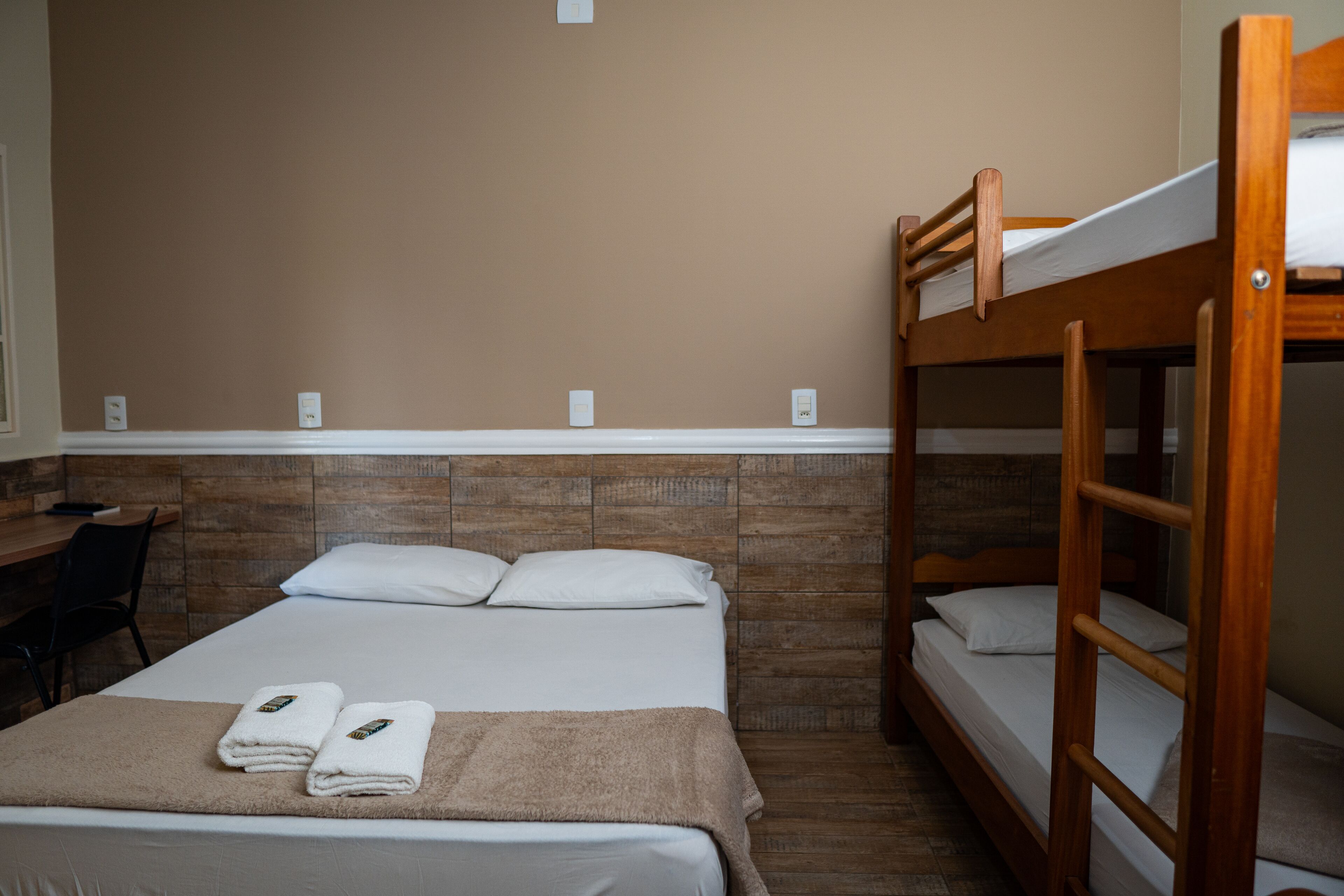 A hotel room with a bunk bed, a desk, and a chair.