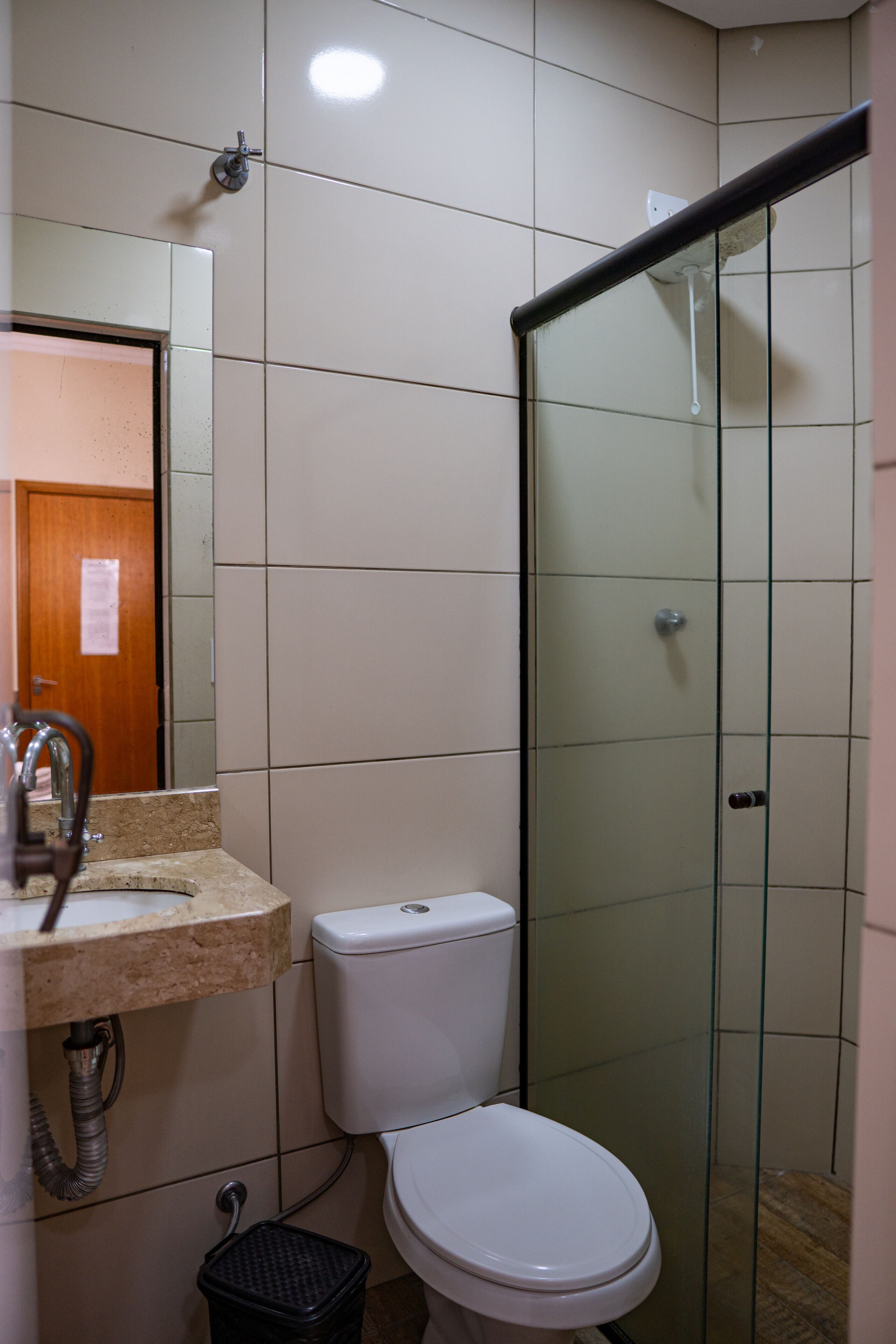 A bathroom with a toilet, sink, and glass shower enclosure.
