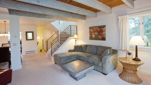 Una sala moderna con un sofá modular, una escalera y un comedor.