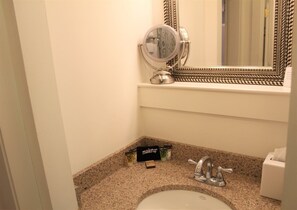 Une salle de bain avec un comptoir en granit, un lavabo, un miroir et une coiffeuse avec miroir.