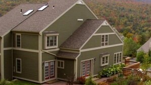 A two-story house with a green exterior, a front porch, and a driveway. - 3BR Overlook at Topnotch (Stowe)