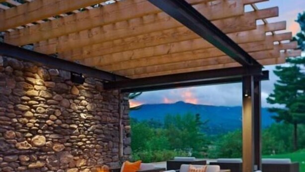 An outdoor seating area with a stone wall, a fire feature, and a view of a mountainous landscape. - 3BR Overlook at Topnotch (Stowe)