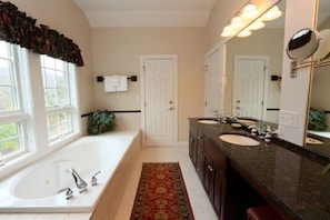 A bathroom with a large bathtub, two sinks, a mirror, and a door. - 627a_topnotch (Stowe)