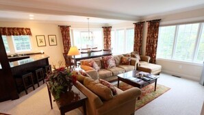 A living room with a sofa, armchair, coffee table, and a dining area with chairs and a table. - 627a_topnotch (Stowe)