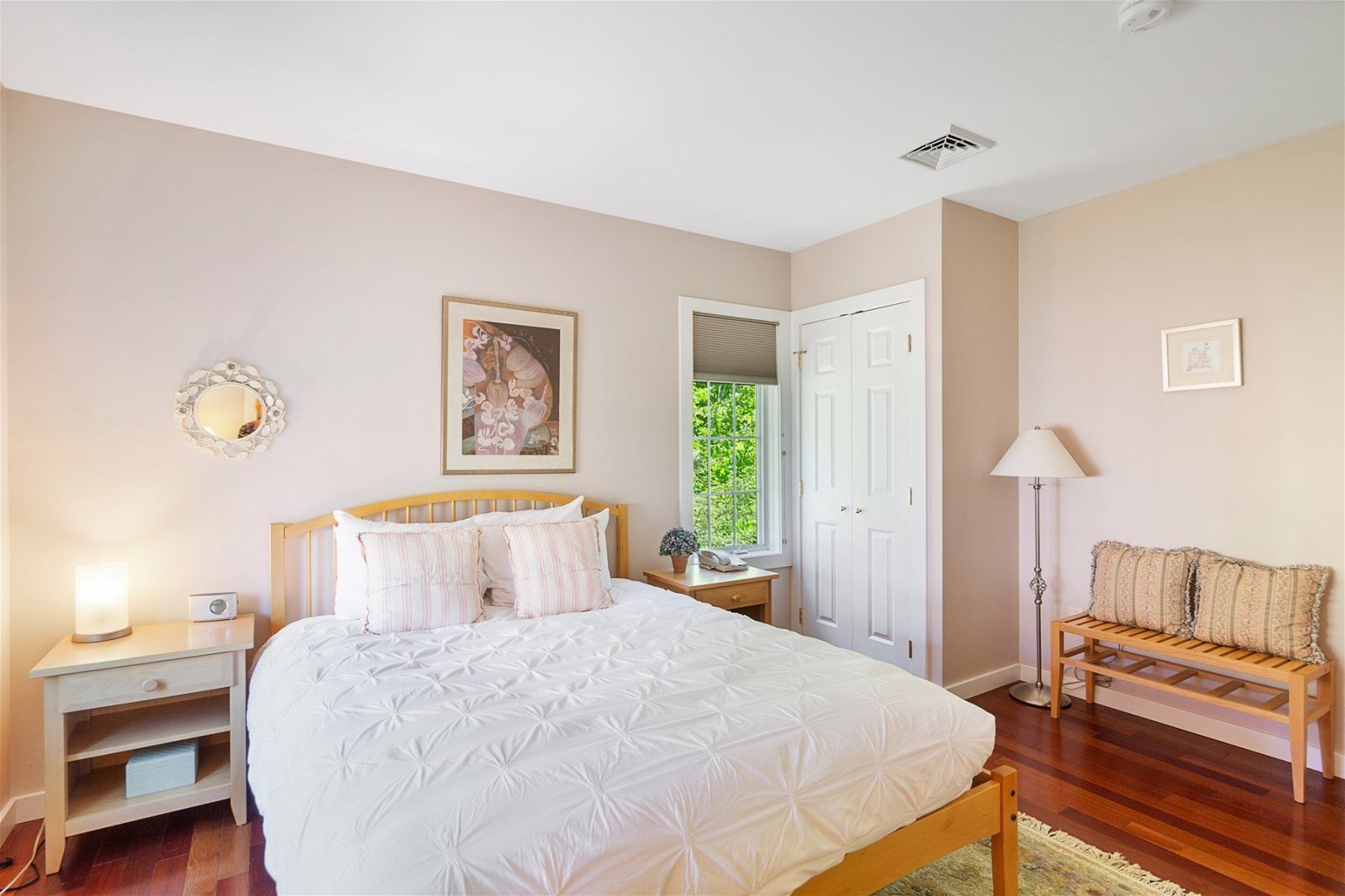 A bedroom with a bed, bedside tables, a nightstand, a lamp, a chair, a door, and a window.
