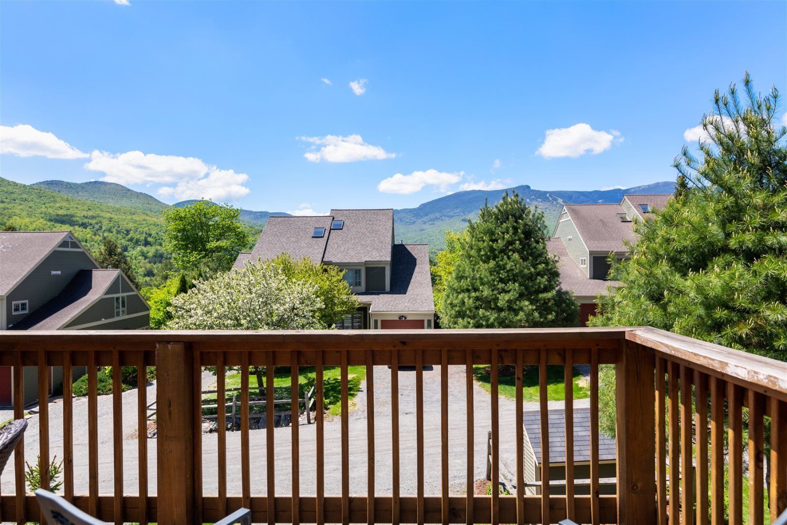 A residential area with houses, a wooden deck, and a mountainous landscape in the background.