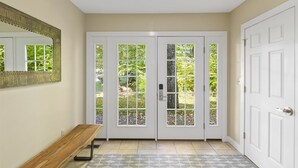 A hallway with a bench, double doors with glass panels, a mirror, and a patterned rug. - Family Friendly Overlook at Topnotch (Stowe)