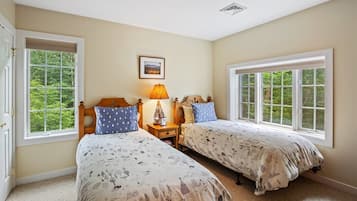 A bedroom with two beds, a nightstand, a lamp, and a framed picture on the wall.