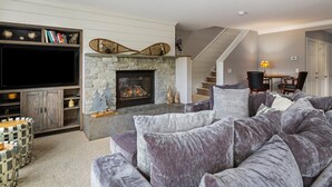 A living room with a stone fireplace, a television, and a large gray sectional sofa. - 3 Bears at Topnotch Resort & Spa (Stowe)
