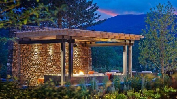 A stone structure with a wooden roof, possibly a gazebo or patio, surrounded by greenery and a mountain in the background. - 3 Bears at Topnotch Resort & Spa (Stowe)