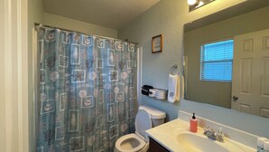 Ein Badezimmer mit Toilette, Waschbecken und Duschvorhang mit Muschelmuster.