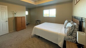 Ein Schlafzimmer mit Bett, Nachttisch, Fenster, Tür und Deckenleuchte.