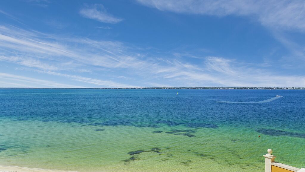 Una vista despejada de una playa con aguas tranquilas y una orilla lejana.
