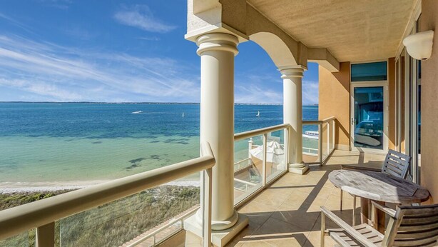 Un balcon avec vue sur l’océan, une table et deux chaises.