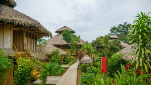 Un resort con cabañas de techo de paja, un sendero central y abundante vegetación.