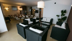 A modern lounge area with wicker furniture, a glass coffee table, and ambient lighting. - Villa del Mar (Bari)