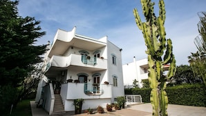 A two-story building with a white exterior, balconies with blue railings, and a cactus in the foreground. - Villa del Mar (Bari)